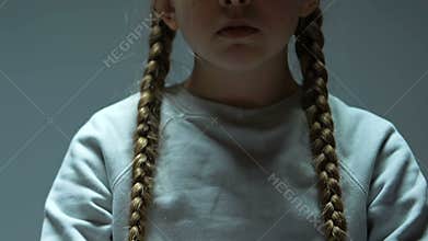 Little scared refugee girl showing drawing with military actions into camera