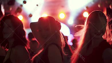 Friends dancing in the spotlight at a disco in a nightclub. girls dancing in a crowd of people
