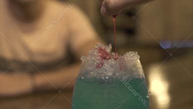 Barman pouring red liquor on ice while making alcoholic cocktail at bar counter in pub. Close up bartender making