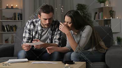 Sad couple checking bank receipts at home