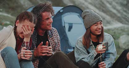 Portrait of young friends multicultural spending a nice time together in the middle of mountain , beside of bonfire
