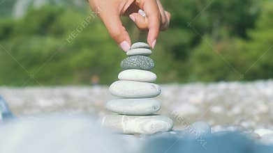 Hand making stone balance at sea beach. Spiritual harmony concept