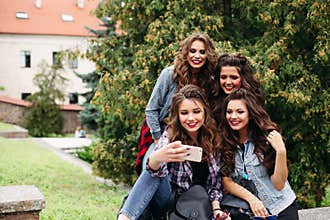 Fashionable ladies with hairstyle taking selfie outdoors.