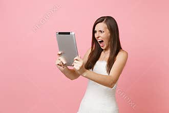 Irritated angry bride woman in wedding dress screaming swearing working on tablet computer making video call on