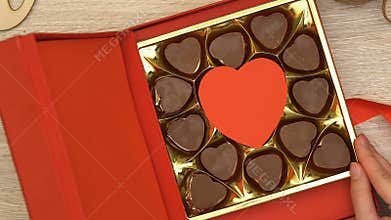Woman open gift box with heart-shaped chocolate candies aphrodisiac, top view