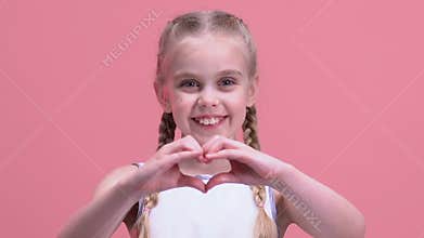 Smiling little girl showing heart gesture, charity, orphan children adoption
