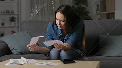 Worried woman checking bank receipts in the night
