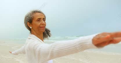 Side view of active senior African American woman exercising on exercise mat at the beach 4k