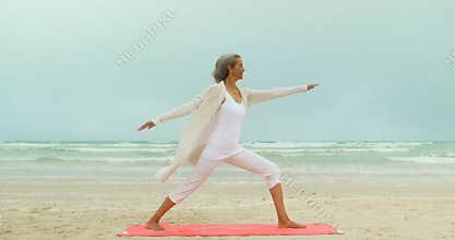 Side view of active senior African American woman exercising on exercise mat at the beach 4k