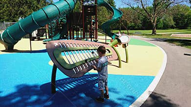 Little boy playing large Xylophone in Riverside Park playground
