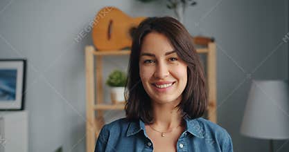 Slow motion portrait of charming young woman looking at camera smiling at home