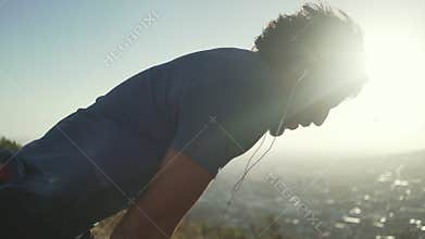 Tired male athlete with earphones in his ears relaxing after exercising