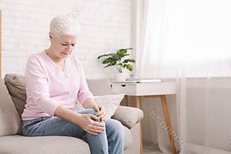 Senior woman suffering from pain in leg, massaging her knee