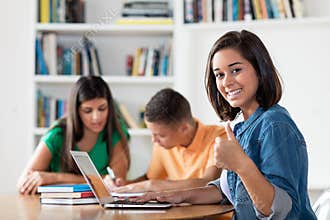 Successful spanish female student with group of learning students