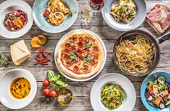 Top of view full table of italian meals on plates and pan. Pizza pasta risotto soup and fish vegetable salad