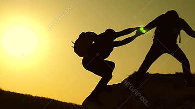 Collaboration climbers travelers at sunset. Silhouettes of men climbing to the top of the mountain. Travelers climb one