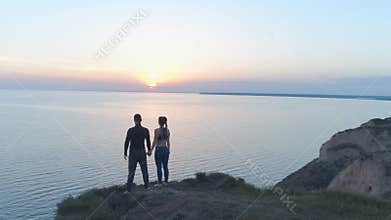 Spiritual freedom, sports happy couple enjoying calmness in nature near sea in sunset standing on hill shore