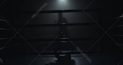 Male boxer training in the dark ring. Slow motion. Silhouette. Boxing concept.