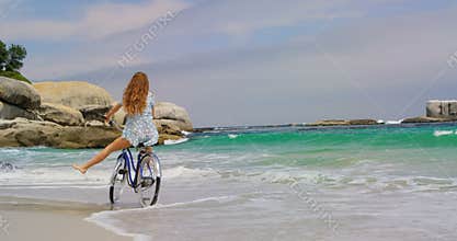 Rear view of Caucasian woman riding a bicycle on the beach 4k