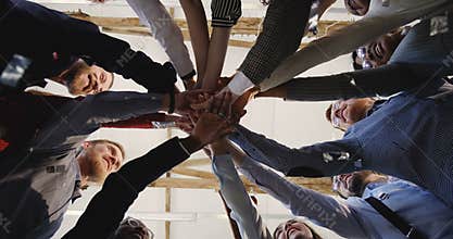 Close-up happy diverse team of business people put hands together, clap and celebrate success under confetti at office.