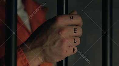 Prisoner with help word on beaten fists holding cell bars, aggression in jail