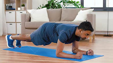 Man with fitness tracker doing plank at home