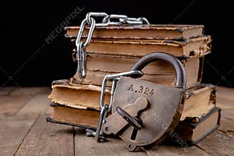Old books bound by a new shiny chain with an old padlock. Forbidden old works artists on a wooden table