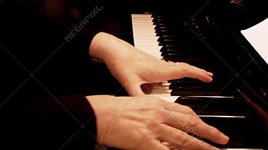 Senior woman`s hands playing piano. Close up side view of elderly hands and fingers playing a song.