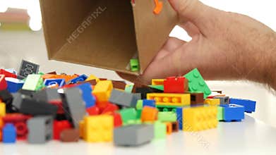 Man Open a Box with Colored Small Plastic Bricks for Toy Constructions