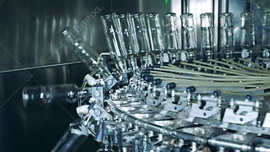 Glass bottles are getting lowered by a factory mechanism