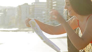 Happy tourist checking map in the coast