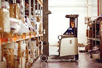 Man on lift operator in uniform at warehouse