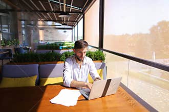 Copywriter typing text on laptop at cafe table.