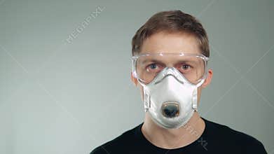 Protective mask on the face. a man puts on his glasses. protection of the respiratory system and eyes.