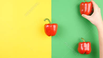 Top view of hand placing sweet red pepper on two colored background