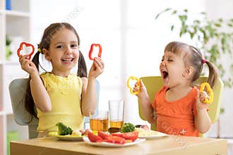 Funny children girls eating healthy food. Kids lunch at home or kindergarten.