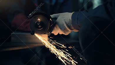 Worker cuts metal with hand disc grinder abrasive saw
