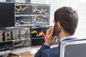 Over the shoulder view of computer screens and stock broker trading online.