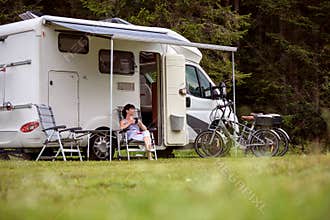 Woman is standing with a mug of coffee near the camper RV.