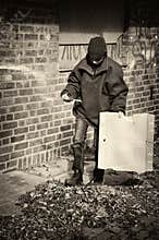 Poor beggar boy in a backyard, his home