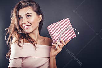 Happy beautiful woman with a gift box for Valentine's day on black background.