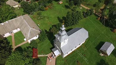 Aerial photography of a small church among village houses and forests.
