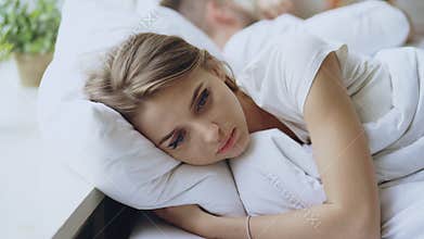 Depressed young woman lying in bed and feeeling upset after quarrel with her boylfriend in bed at home
