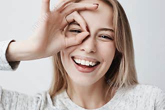 Close up portrait of beautiful joyful blonde Caucasian female smiling, demonstrating white teeth, looking at the camera