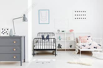 Lamp on grey cabinet in kids bedroom interior with posters above