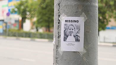 Leaflet about the missing child hanging on a pole,slow mo