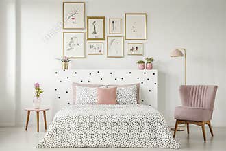Feminine bedroom interior with a double bed with dotted sheets,