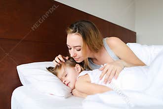 Young pretty mother sleeping with daughter and kissing.