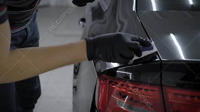 Close up shot of a man in gloves ceramic coating clean black car.