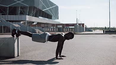Street workout. Athletic African American man doing push-ups and spin exercise on outdoors. A black man is playing